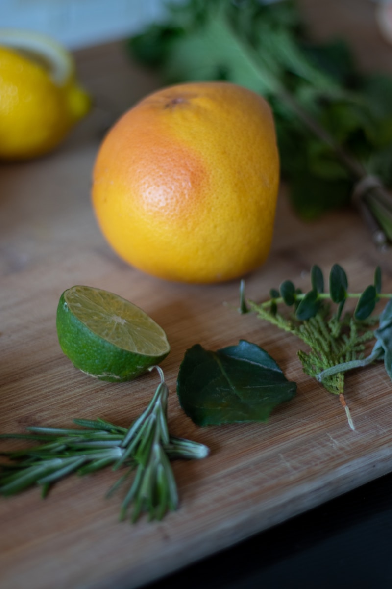 a wooden cutting board topped with oranges and herbs